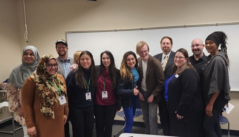 A dozen officers, candidates, and guests posed together at the front of a classroom