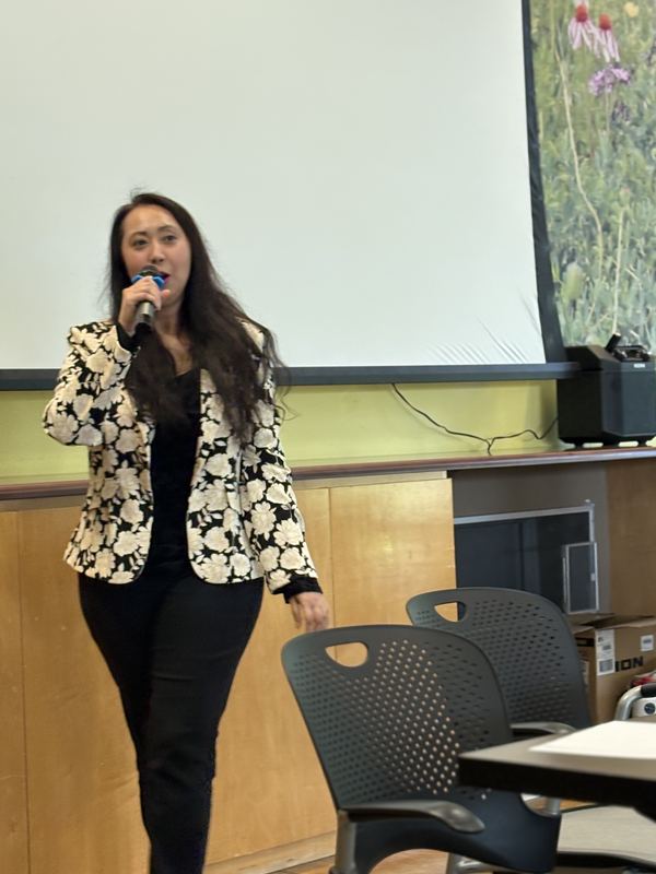 A chapter officer speaking into a microphone in front of a projection screen