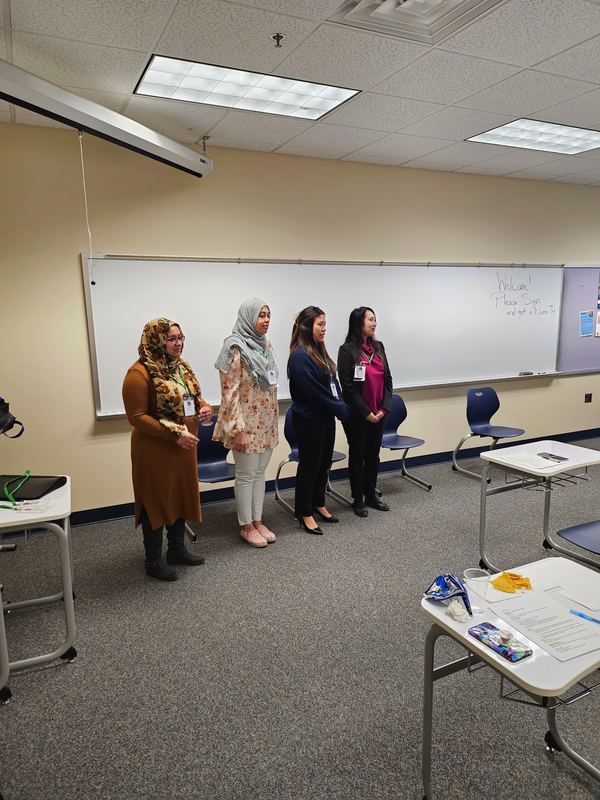 Four women officers wearing name badges standing at the front of a classroom